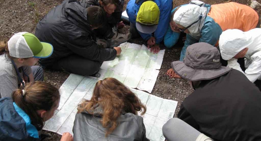 a group of teens examine maps on a backpacking expedition with outward bound
